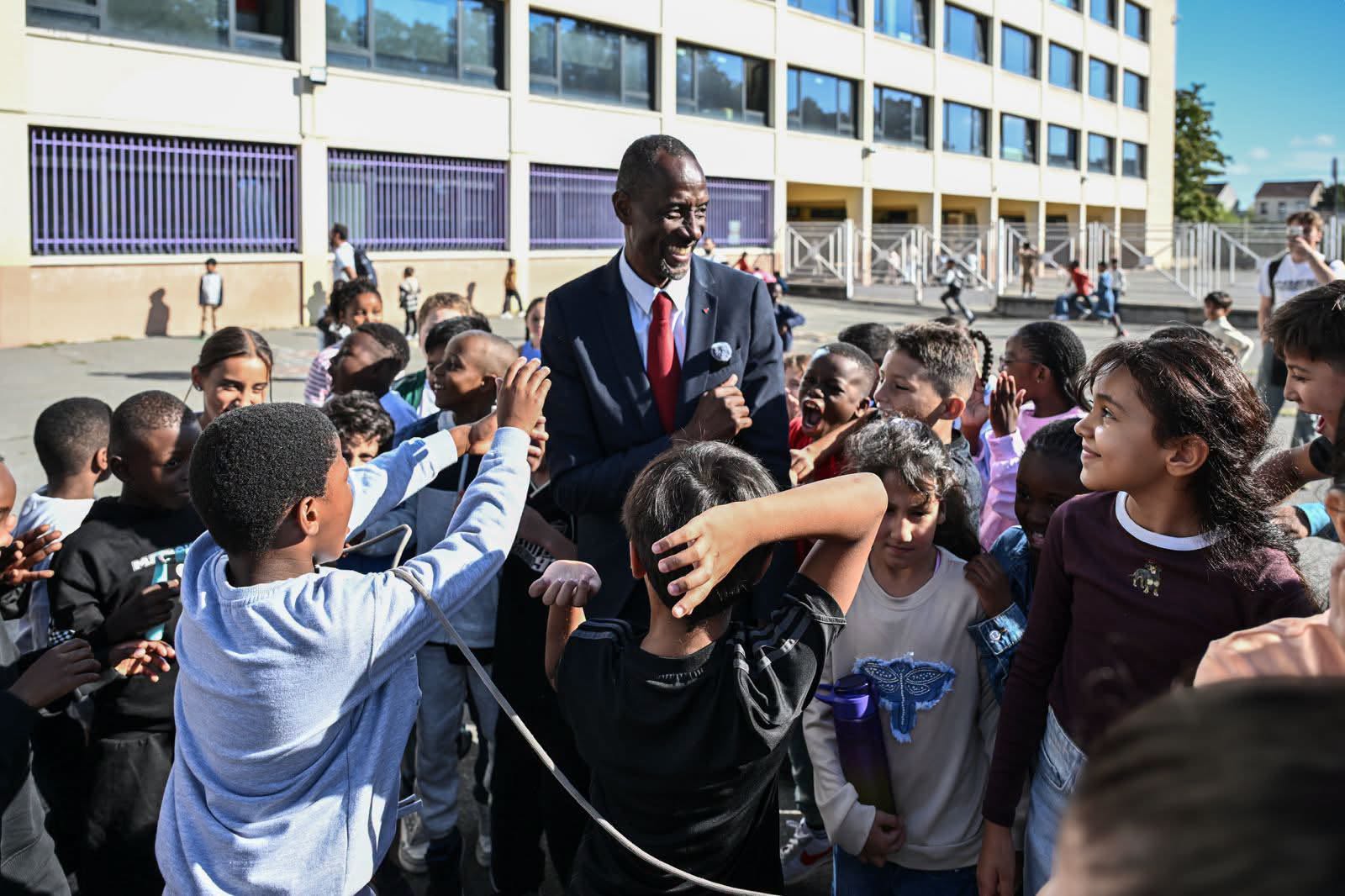 Bally Bagayoko entouré d'élèves dans la cour d'une école de Saint-Denis–Pierrefitte lors de la rentrée scolaire